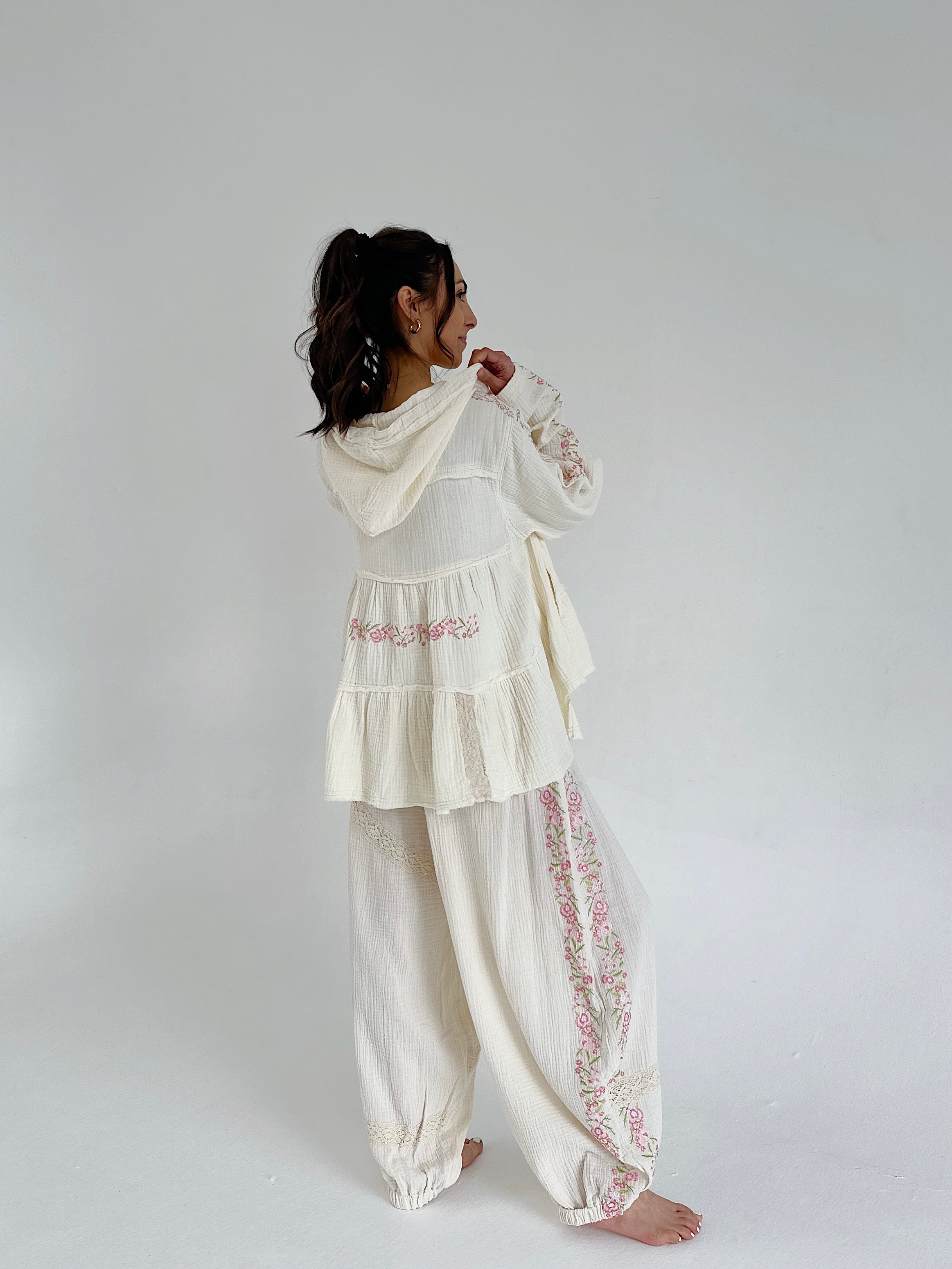 Person wearing a white embroidered outfit on a plain background
