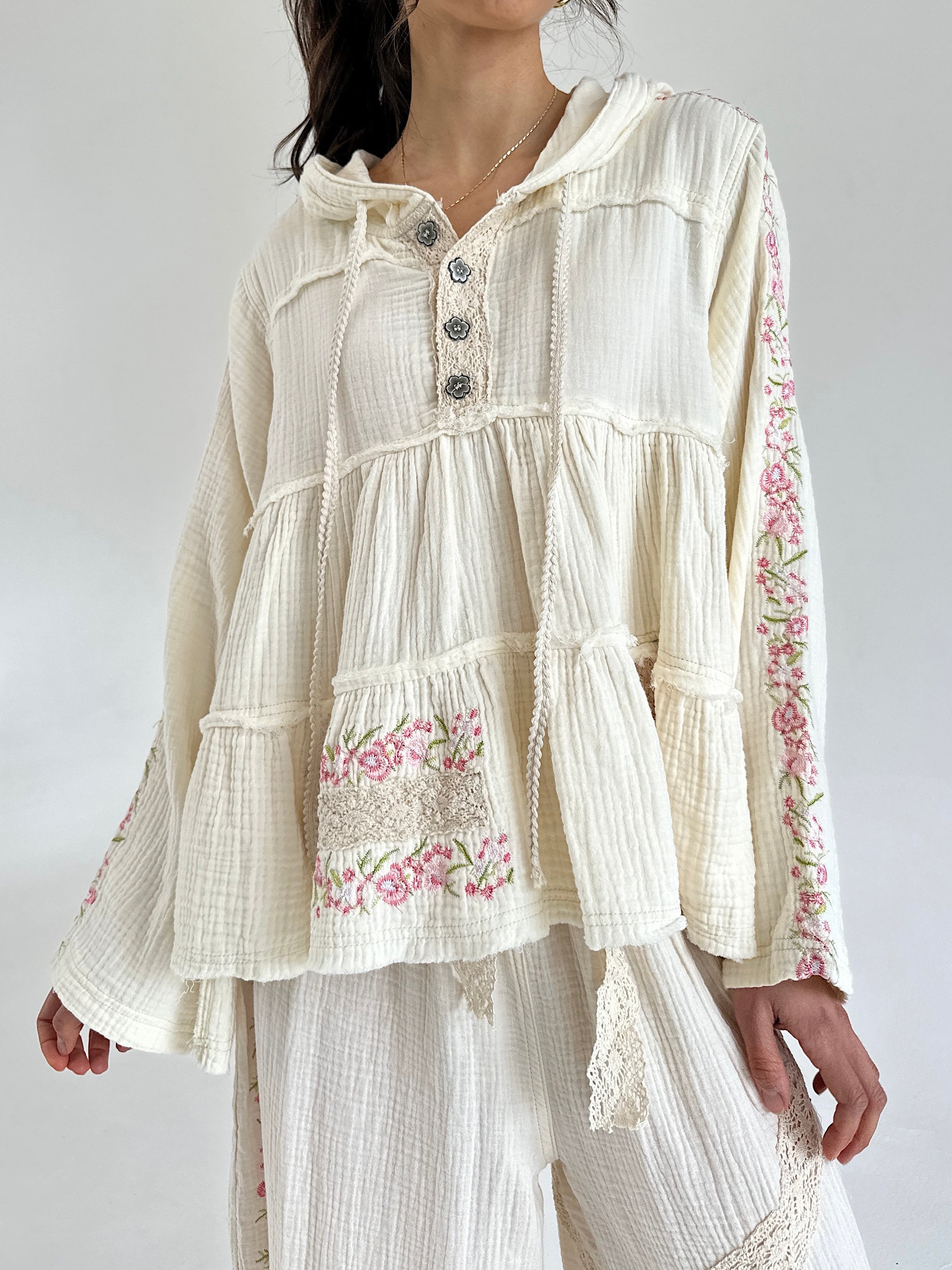 Woman wearing a cream-colored blouse with floral embroidery on a white background