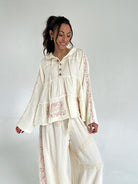 Woman wearing a cream-colored outfit with floral embroidery on a white background