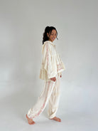 Woman wearing a cream-colored embroidered outfit on a plain background