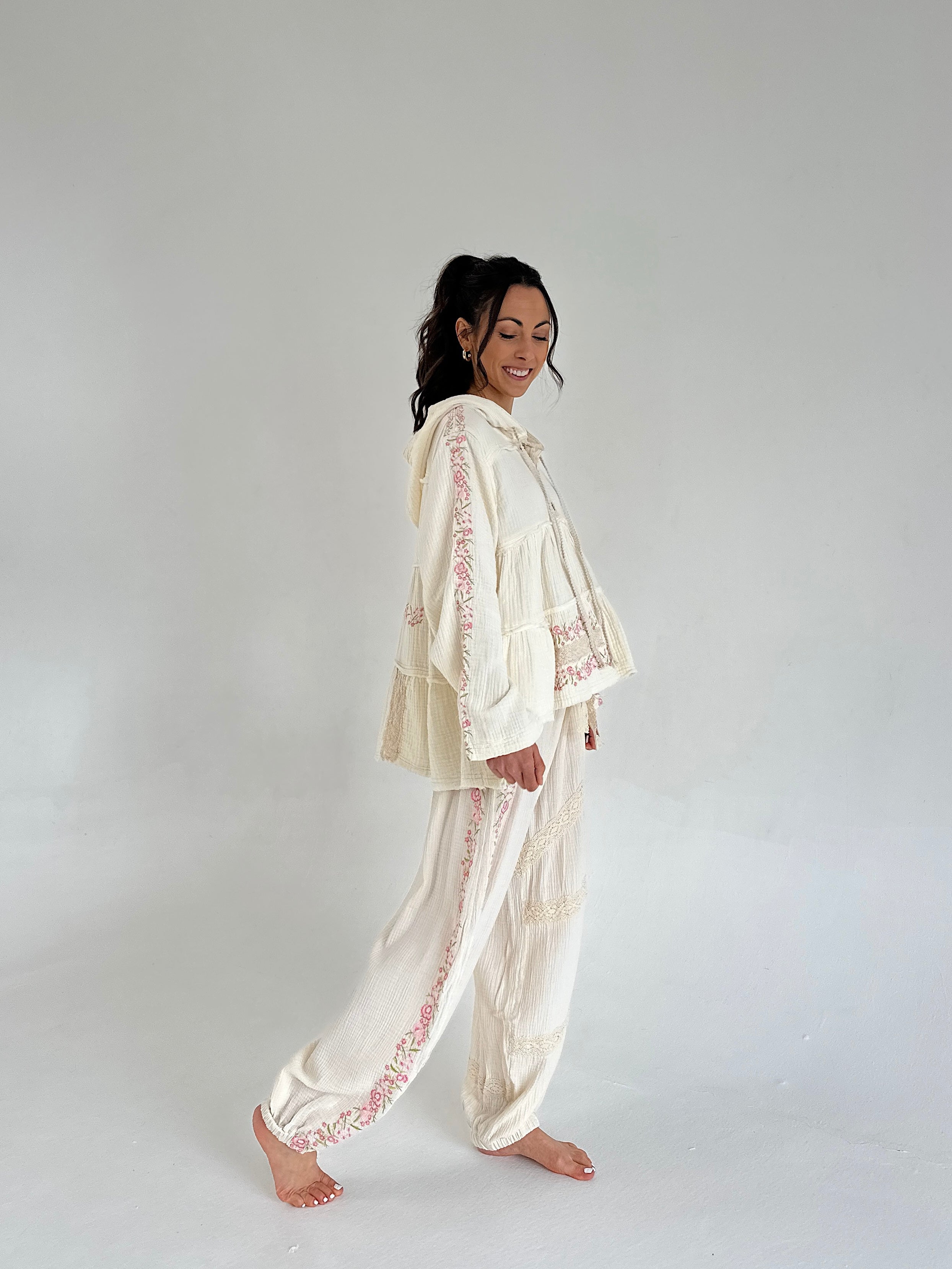 Woman wearing a cream-colored embroidered outfit on a plain background