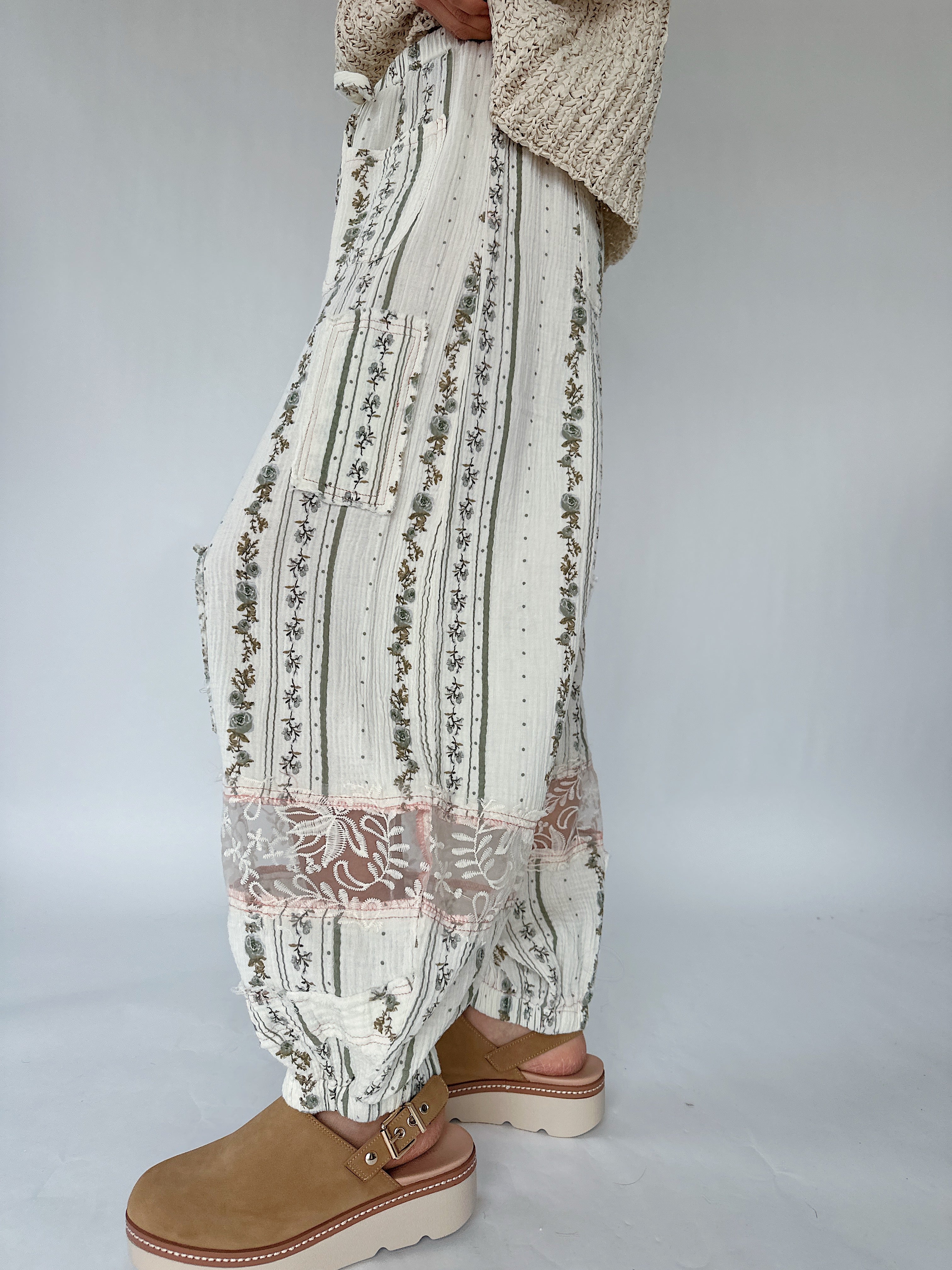 Person wearing patterned pants and brown shoes on a plain background