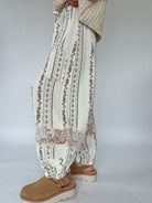 Person wearing patterned pants and brown shoes on a plain background