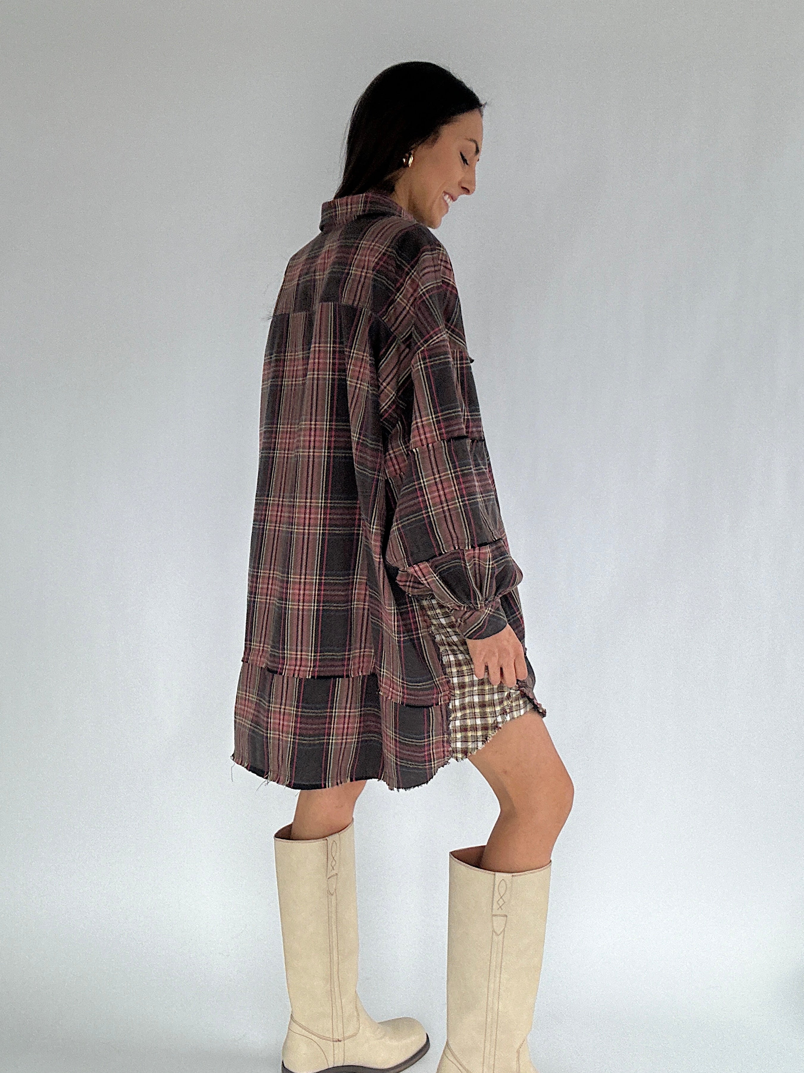 Woman wearing a plaid dress and white boots against a plain background showing the backside