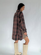 Woman wearing a plaid dress and white boots against a plain background showing the backside