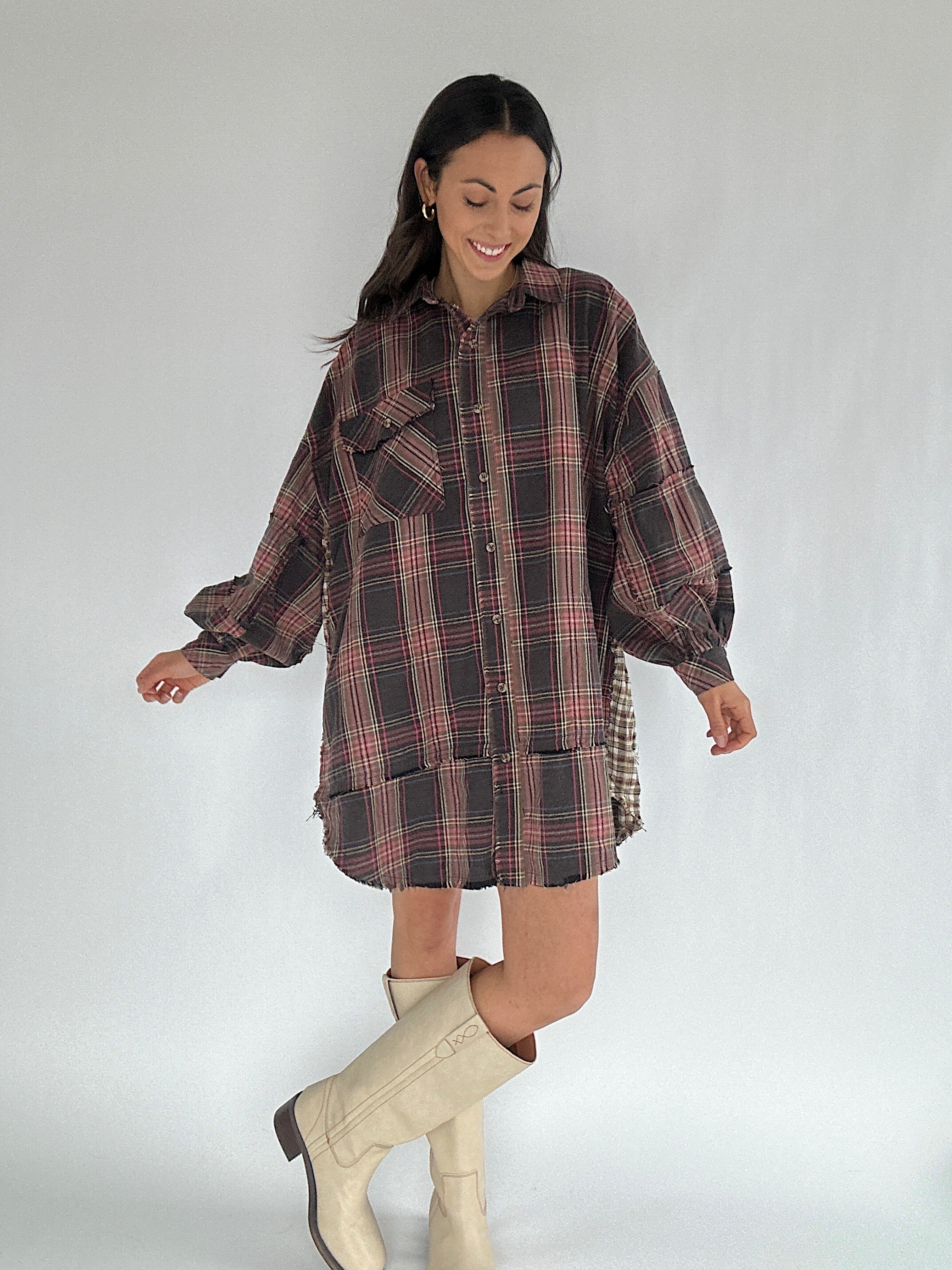 Woman wearing a plaid shirt dress with white boots on a plain background