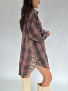 Person wearing a plaid shirt dress with beige boots on a plain background showing contrast side panel