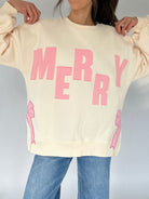 Beige sweatshirt with pink 'MERRY' text and bows on a plain background