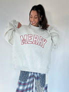 Person wearing a gray sweatshirt with 'MERRY' text, standing against a white background