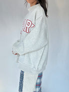 Person wearing a gray sweatshirt with red text on a white background