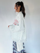 Person wearing a white sweatshirt with red text, standing against a plain background