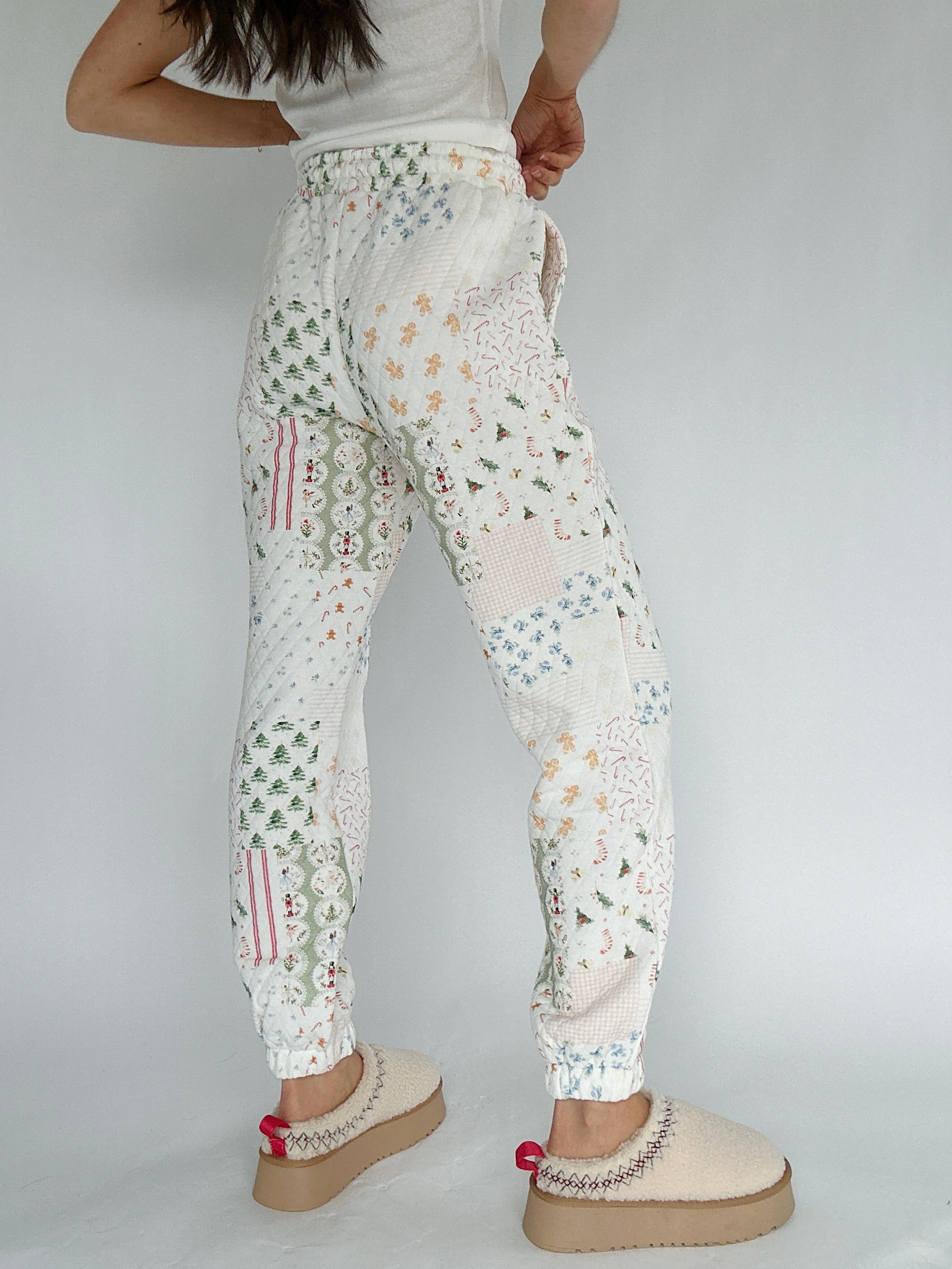 White quilted holiday-patterned jogger pants worn by a person on a plain background showing back