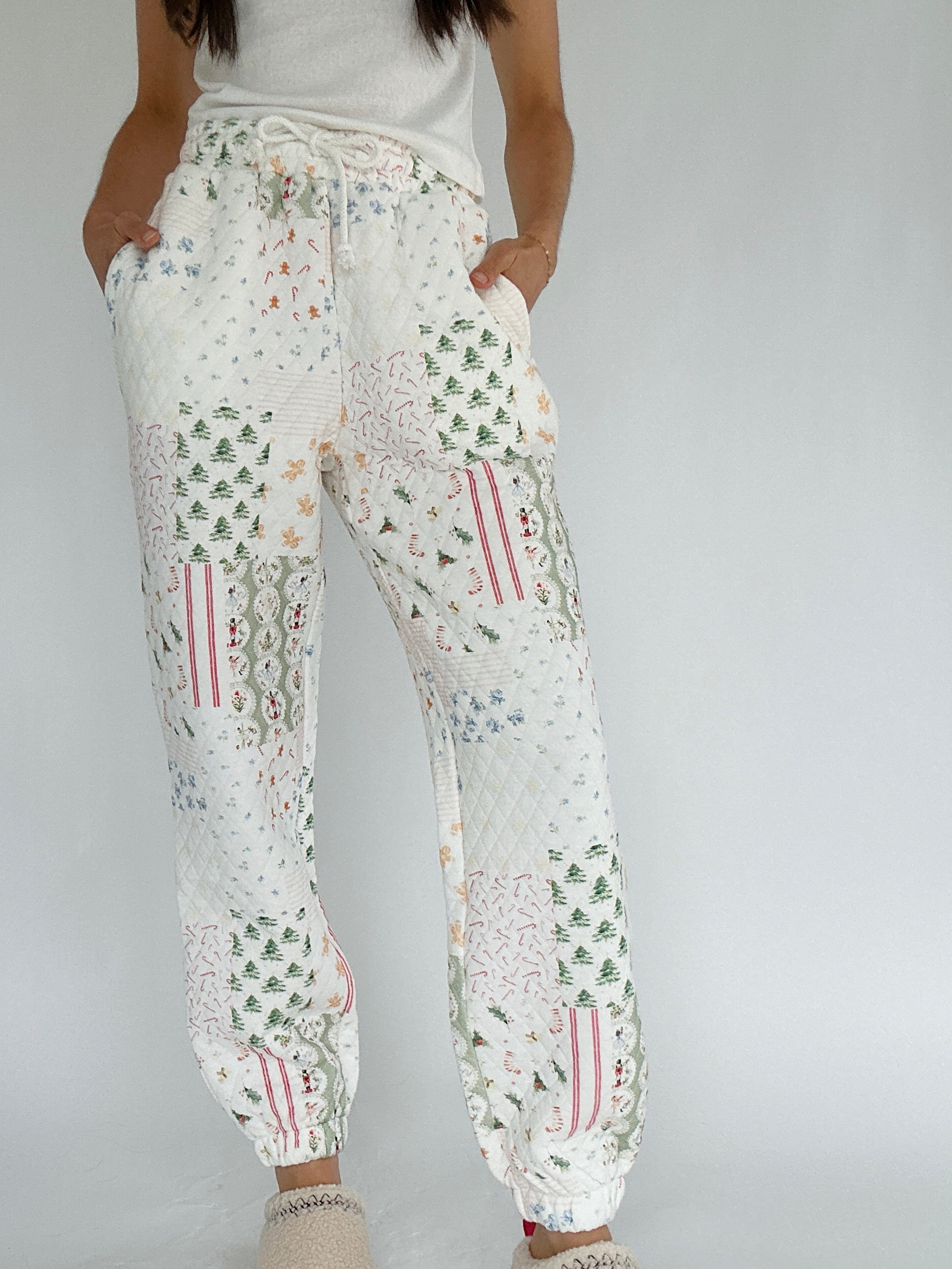 White holiday patterned quilted jogger pants worn by a person on a plain background