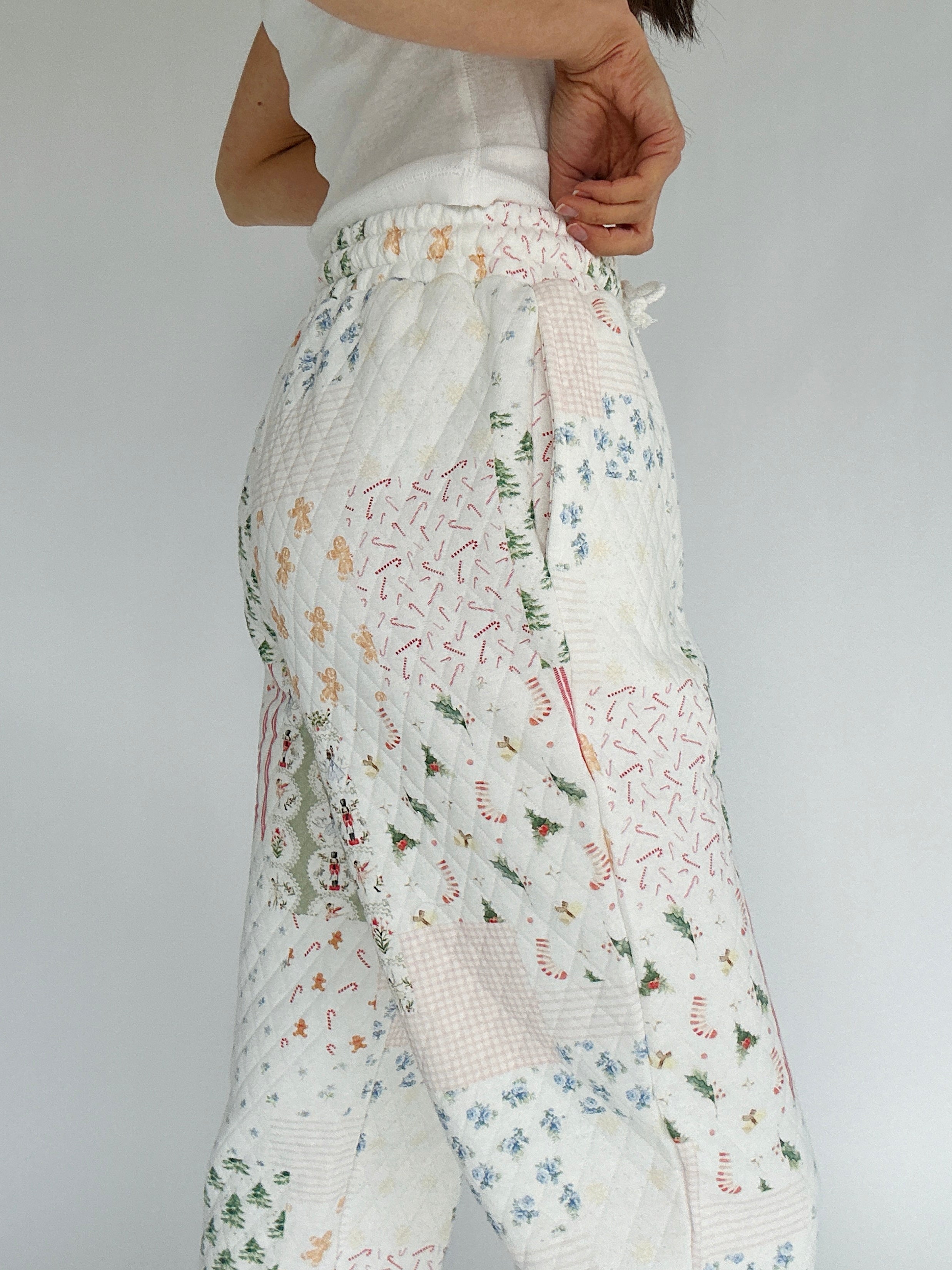 Holiday-patterned pants worn by a person on a plain background showing side pockets