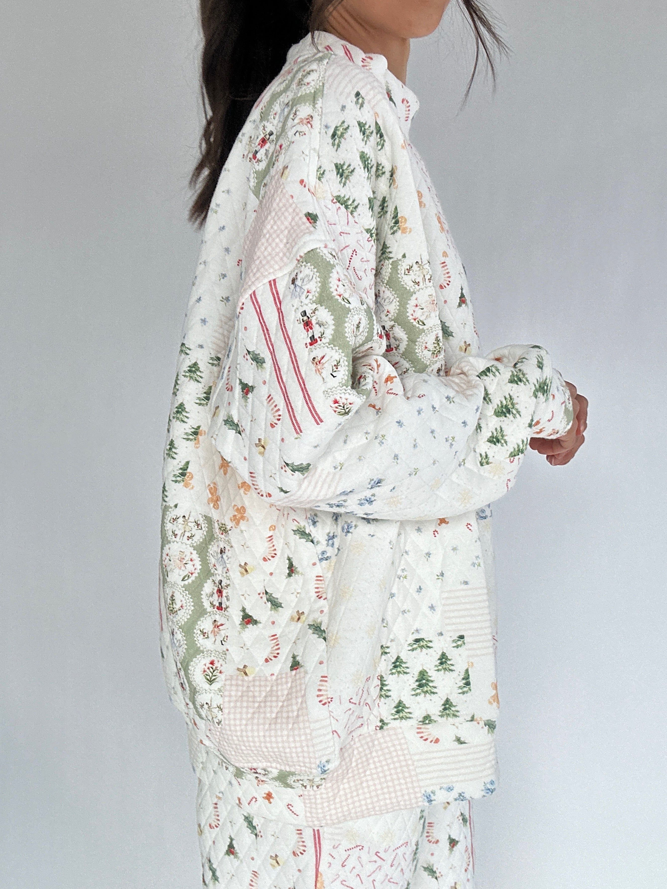 Person wearing a holiday patterned quilted mockneck with a white background from side