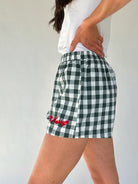 Green and white checkered shorts with red text on a plain background showing side view