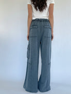 Person wearing smoke blue cargo pants with a white background from back