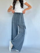 Person wearing smoke blue cargo pants and a white top on a plain background