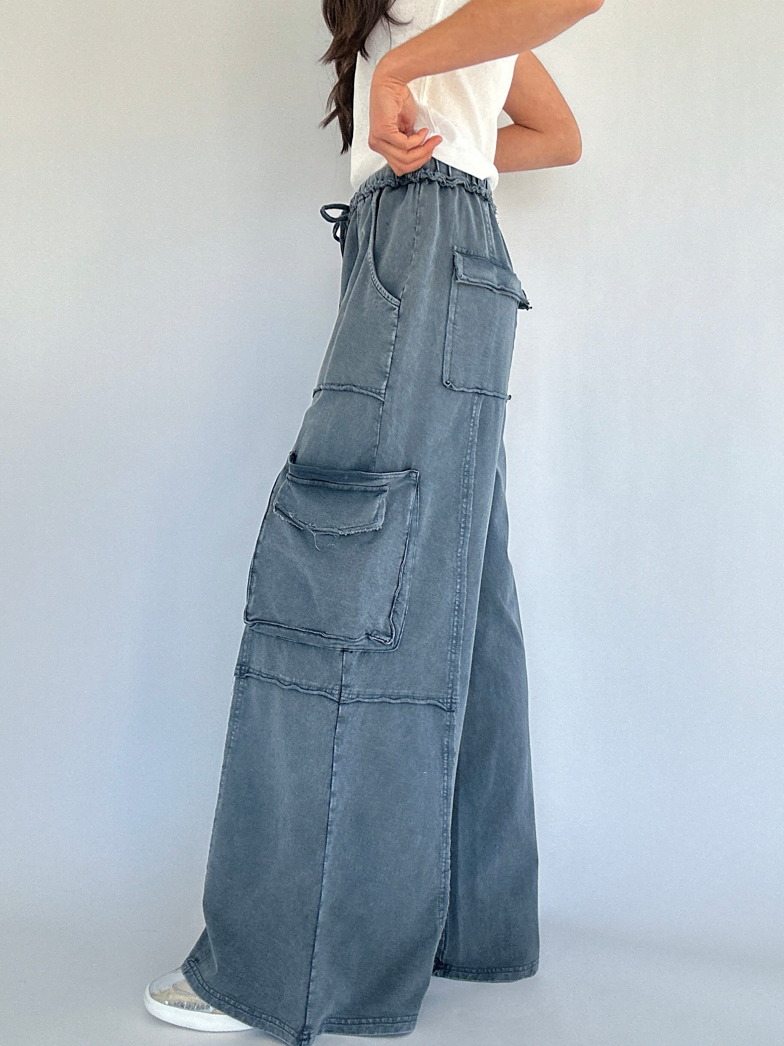 Person wearing wide-leg cargo sweatpants with multiple pockets on a plain background