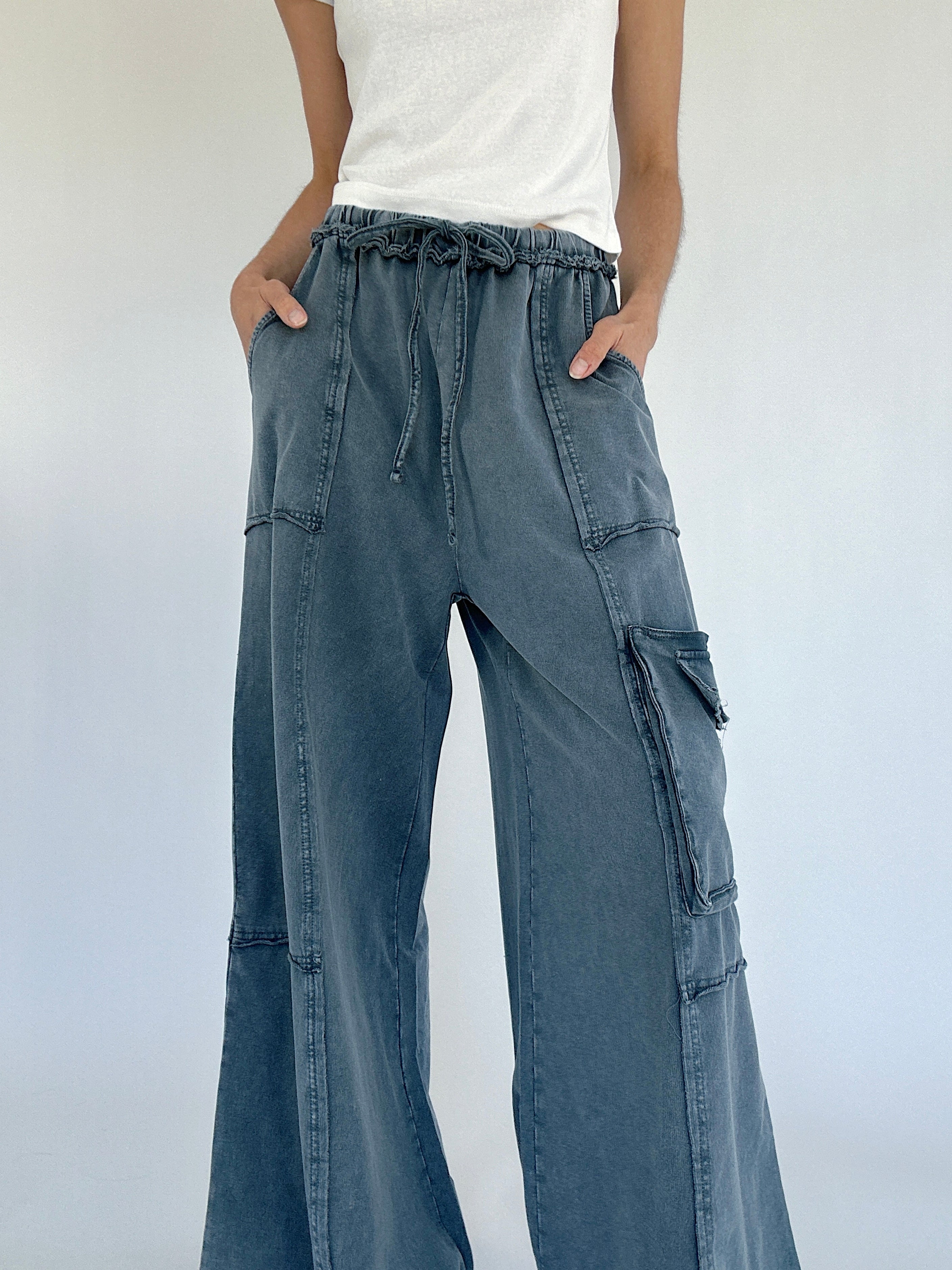 Person wearing smoke blue cargo pants with a white background showing elastic drawstring waist