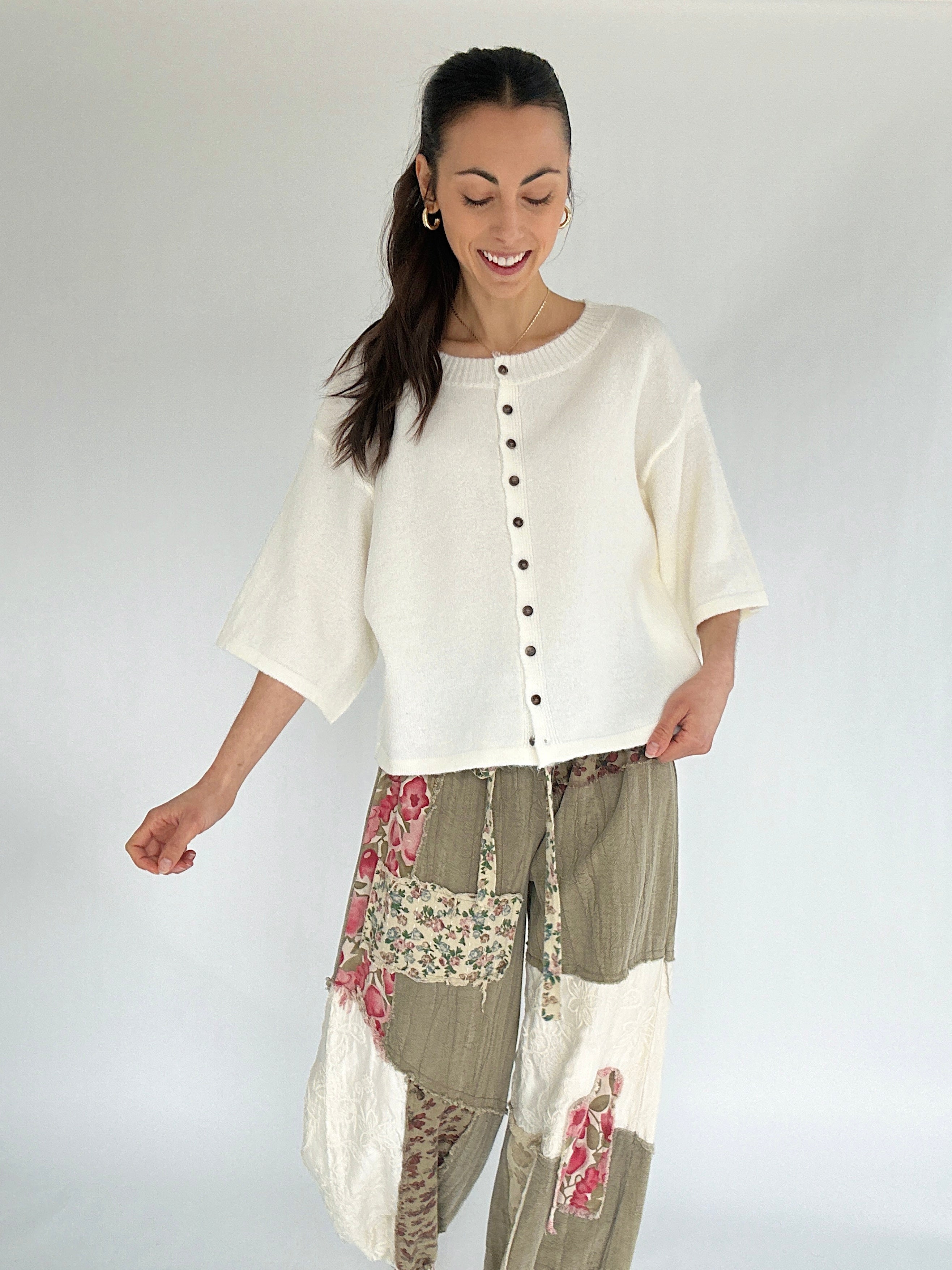 Woman wearing a white top and patterned pants on a plain background