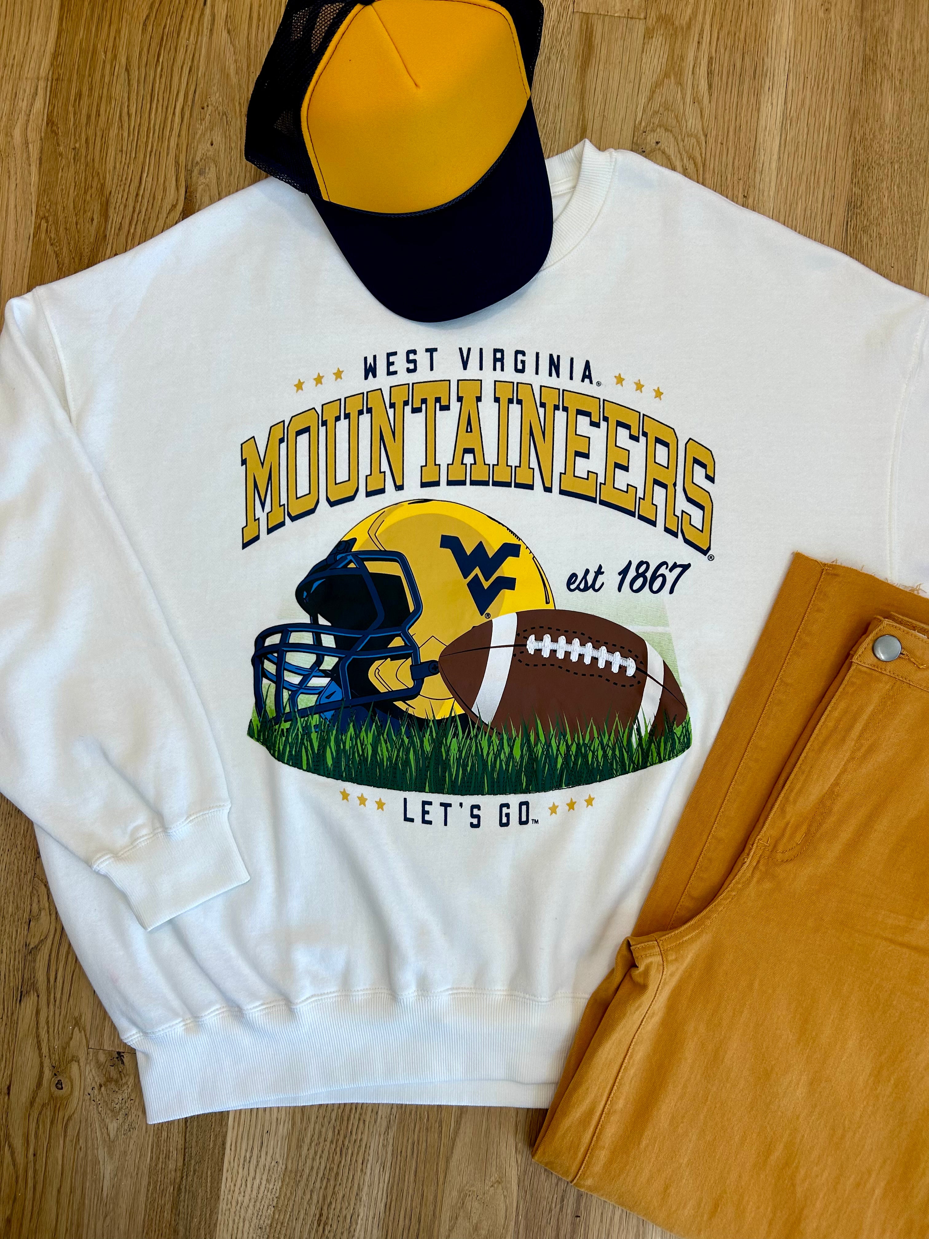 WV Mountaineers Football graphic on a white sweatshirt with a ballcap and pair of pants folded on the floor.