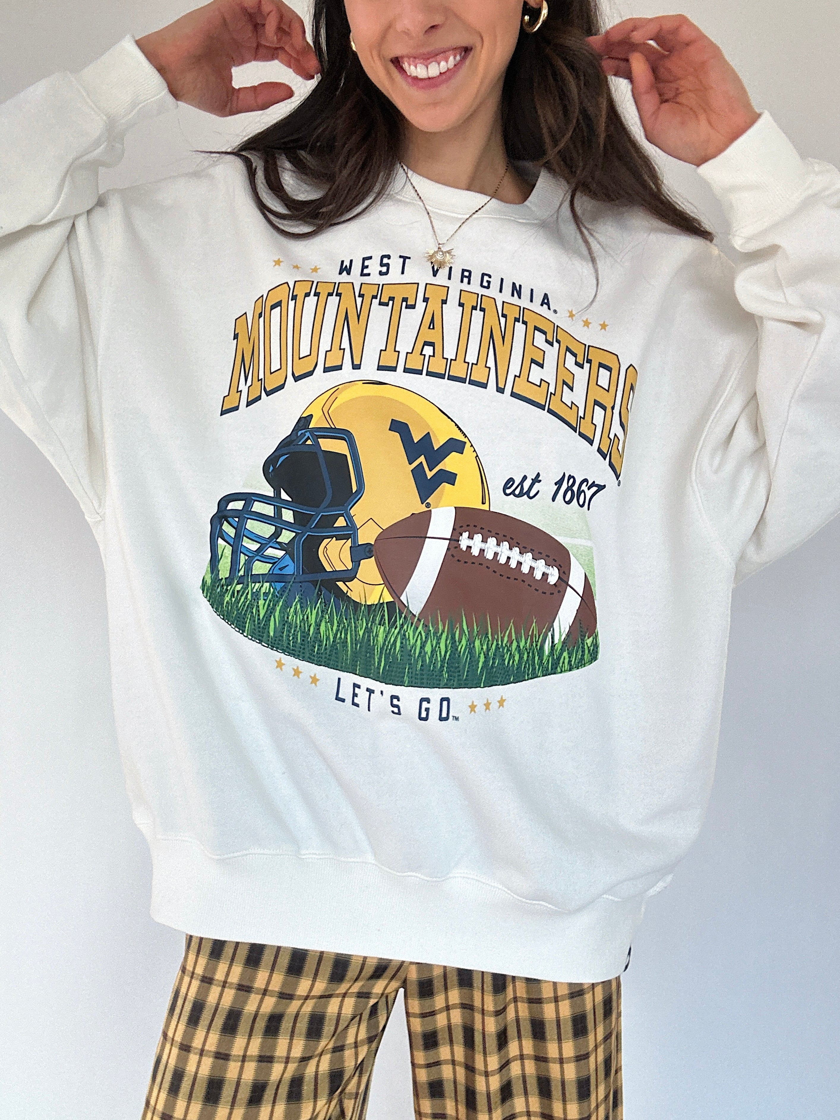 Person wearing a white sweatshirt with West Virginia Mountaineers football graphic design.