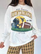 Person wearing a white sweatshirt with West Virginia Mountaineers football graphics and text.