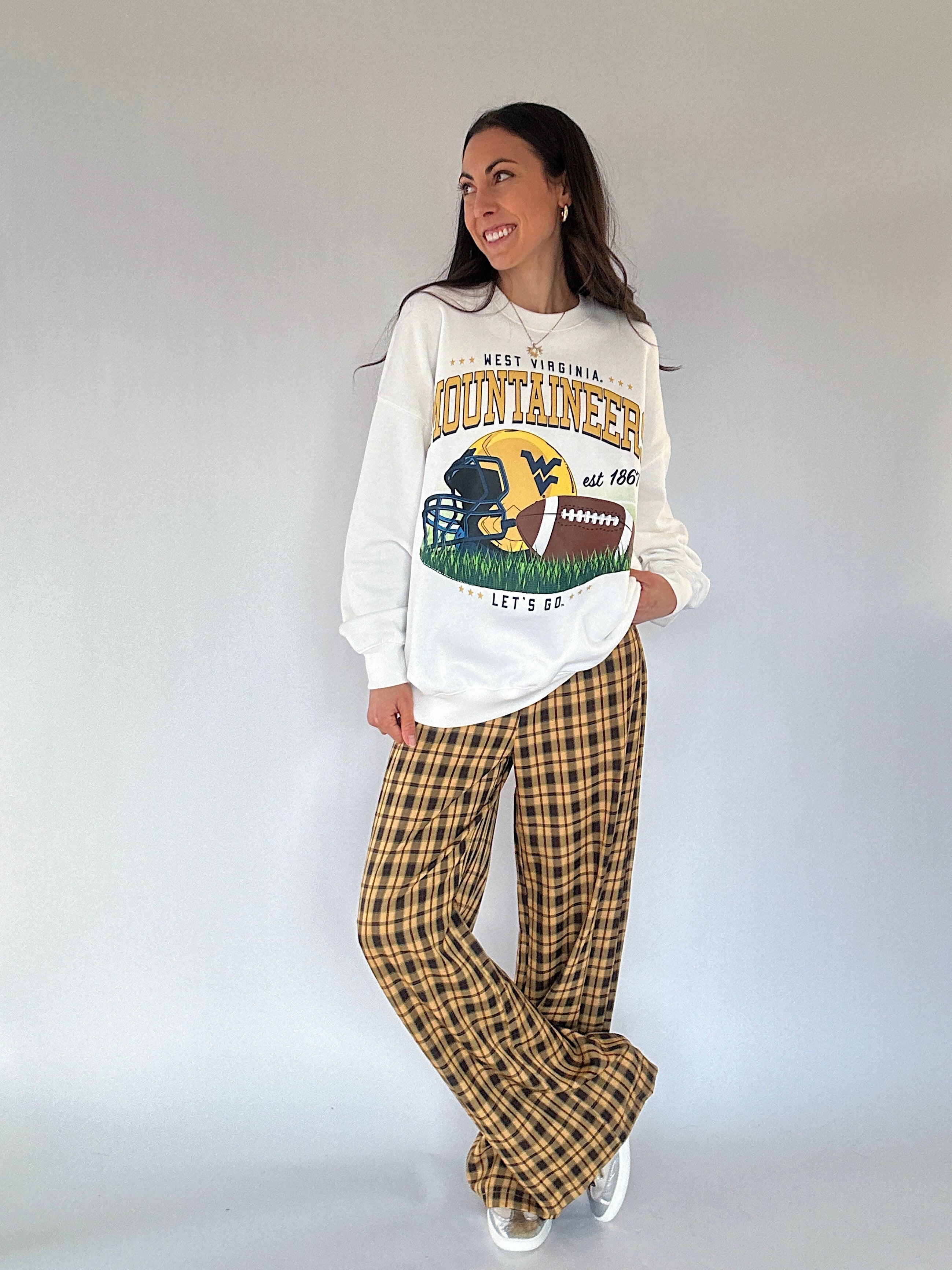 Person wearing a Mountaineer sweatshirt and yellow plaid pants against a white background