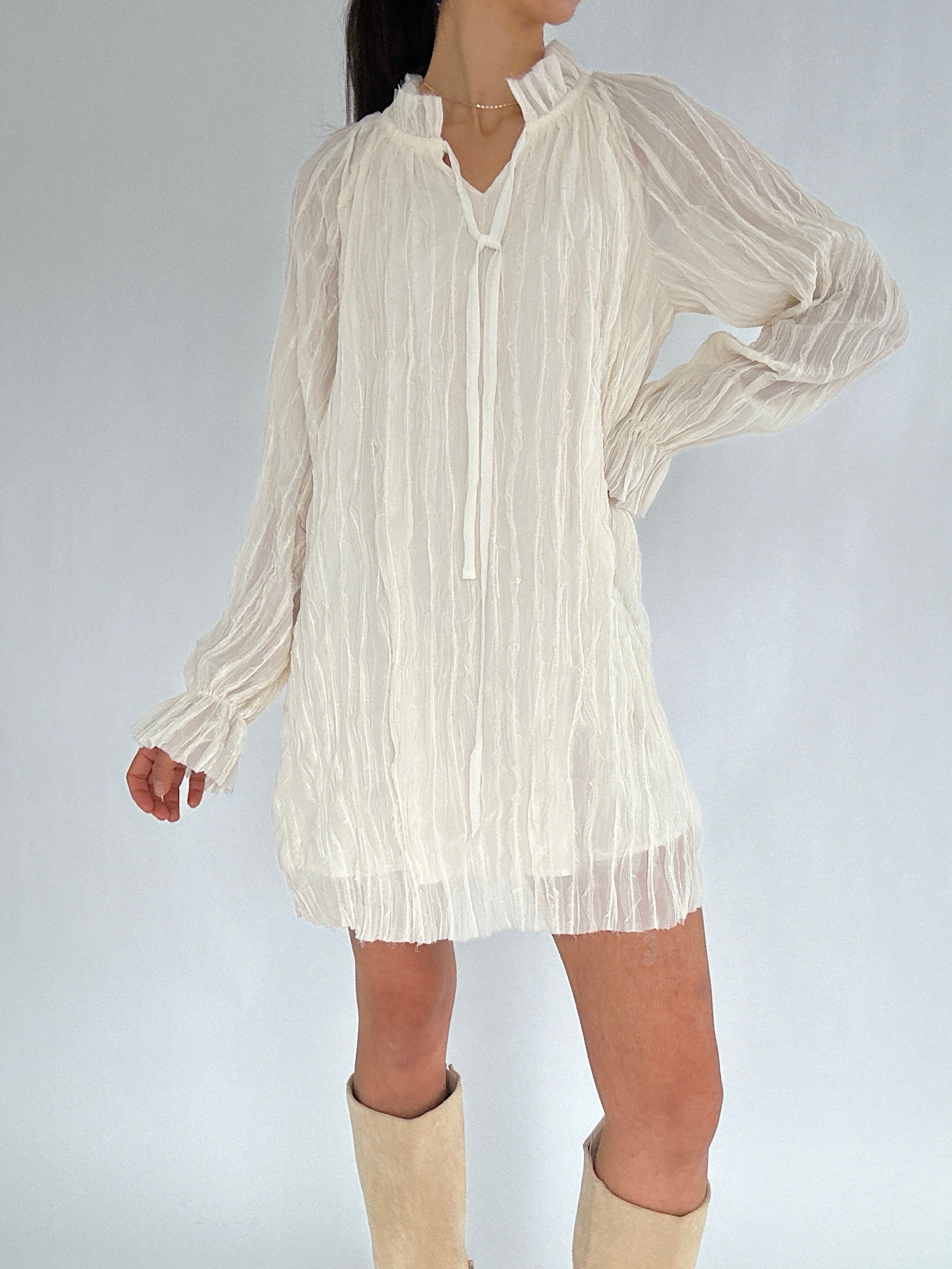 White pleated dress worn by a person on a plain background