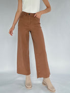 Person wearing brown wide-leg pants on a plain background