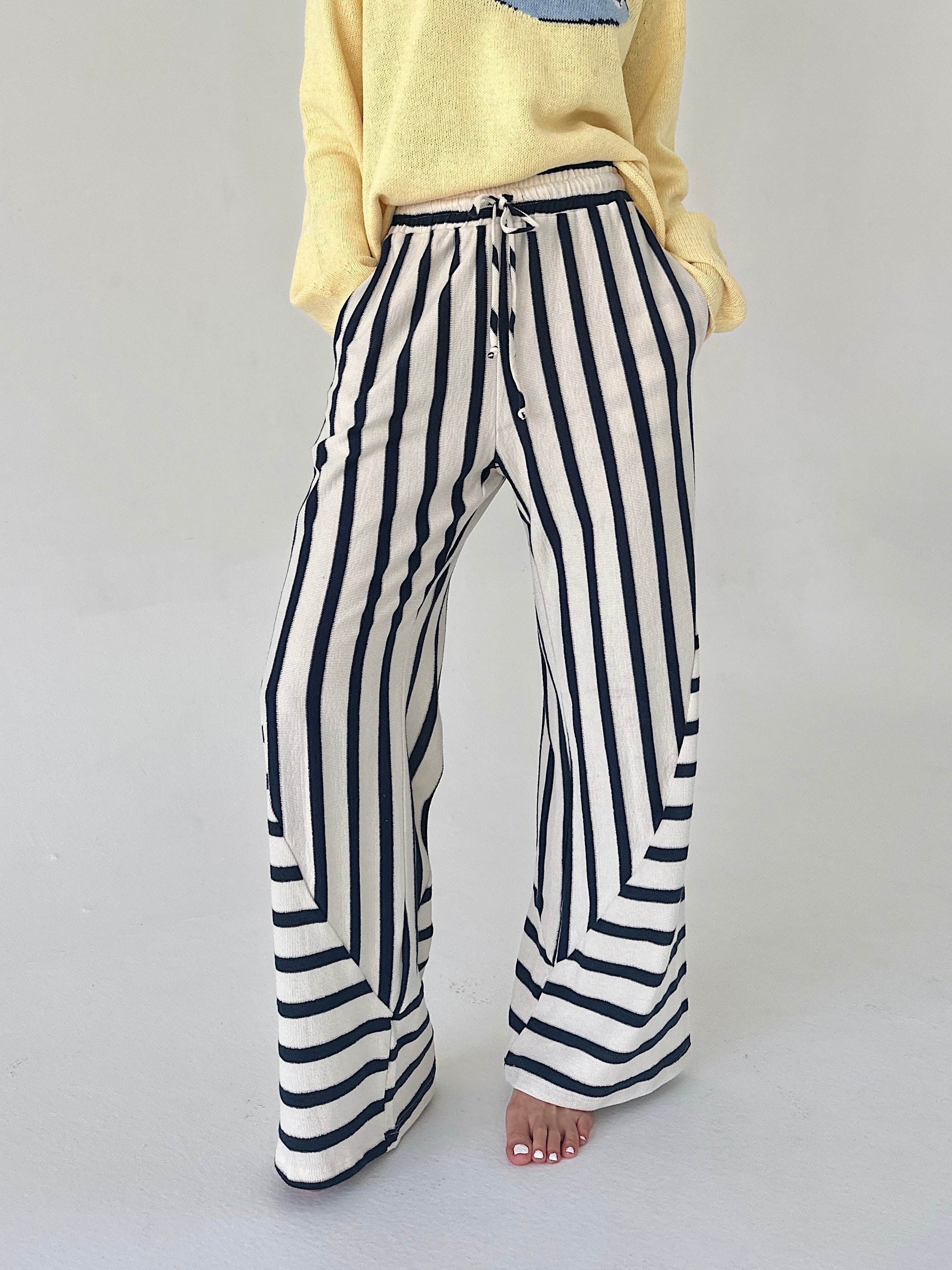 Person wearing navy and white striped pants on a plain background