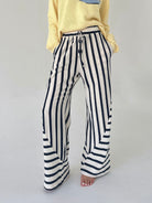 Person wearing navy and white striped pants on a plain background