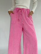 Person wearing pink  wide leg pants with a white background showing drawstring waist