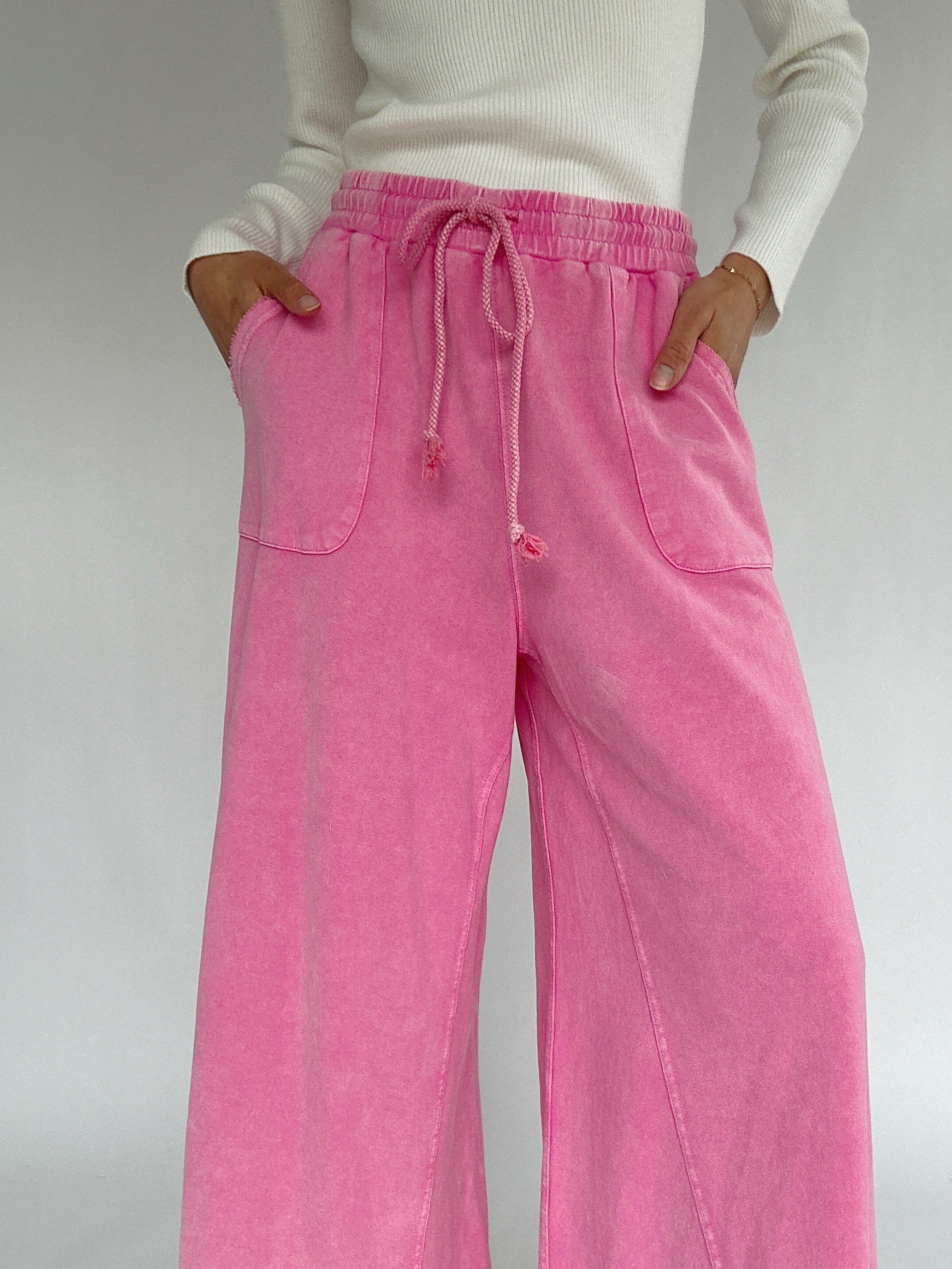 Person wearing pink  wide leg pants with a white background showing drawstring waist
