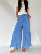 A model wearing light blue wide-leg drawstring pants with a white t-shirt, standing against a plain white studio background.