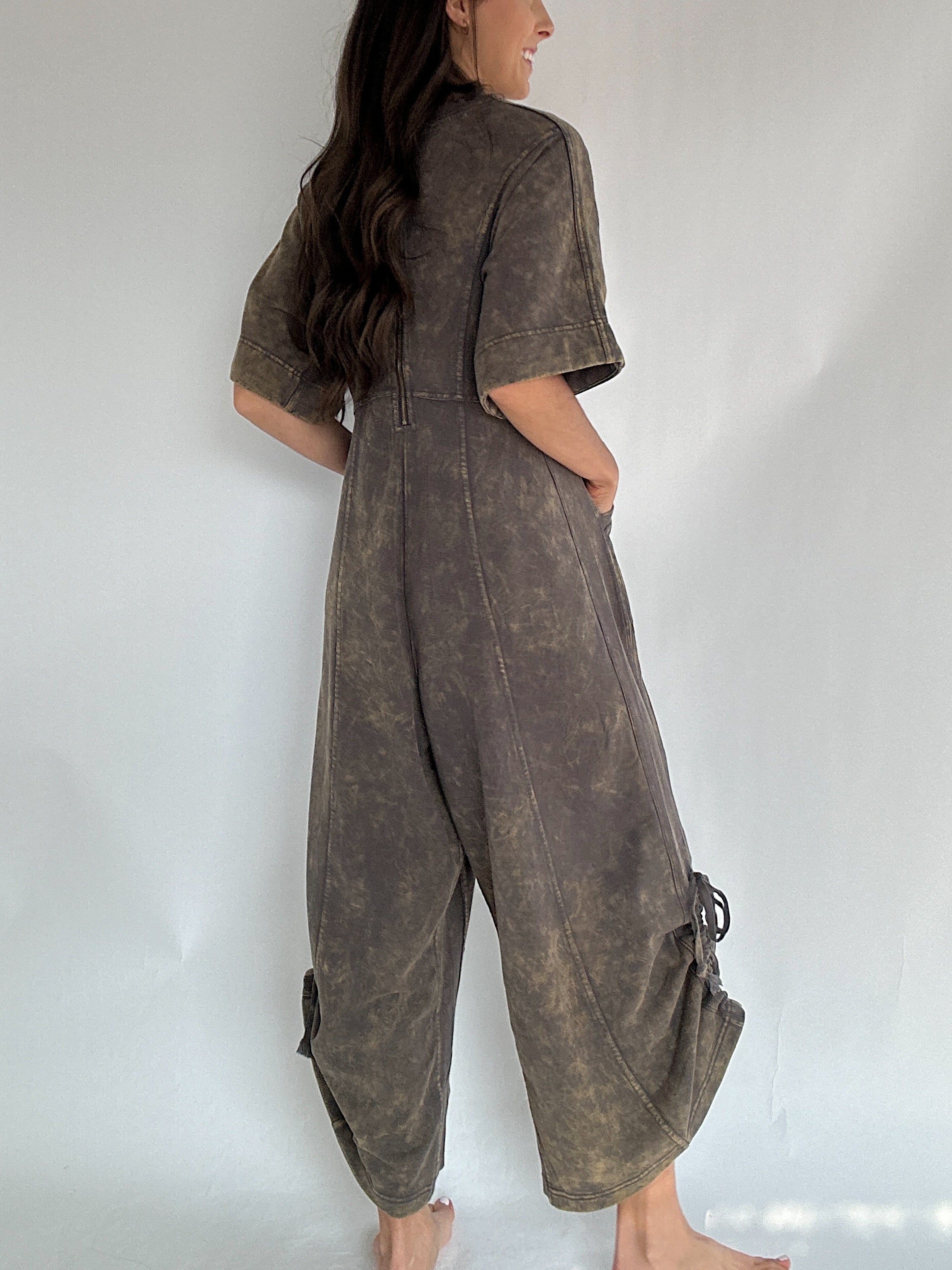 Person wearing a brown terry knit jumpsuit against a white background to show back view