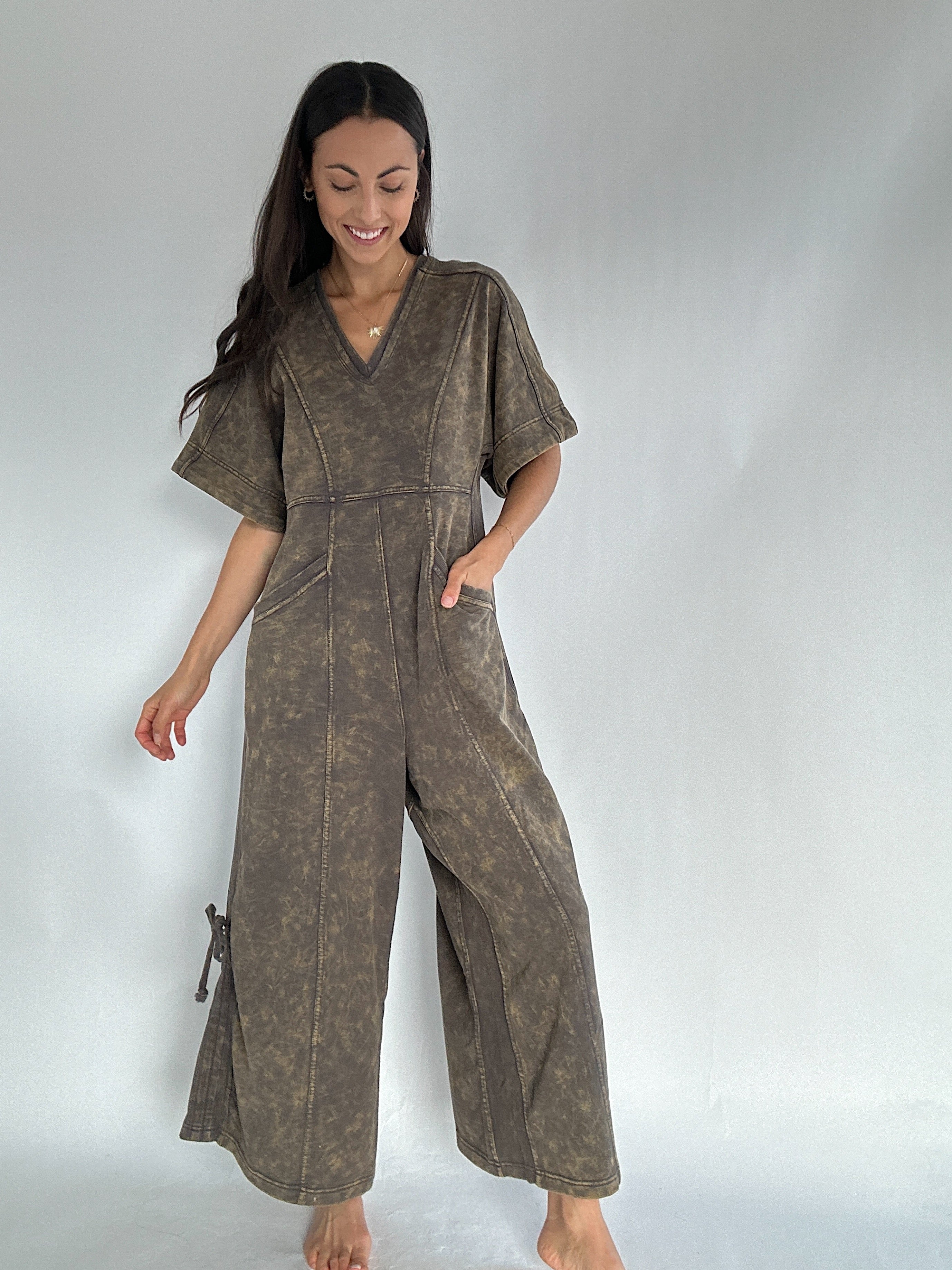 Woman wearing a brown jumpsuit on a plain background