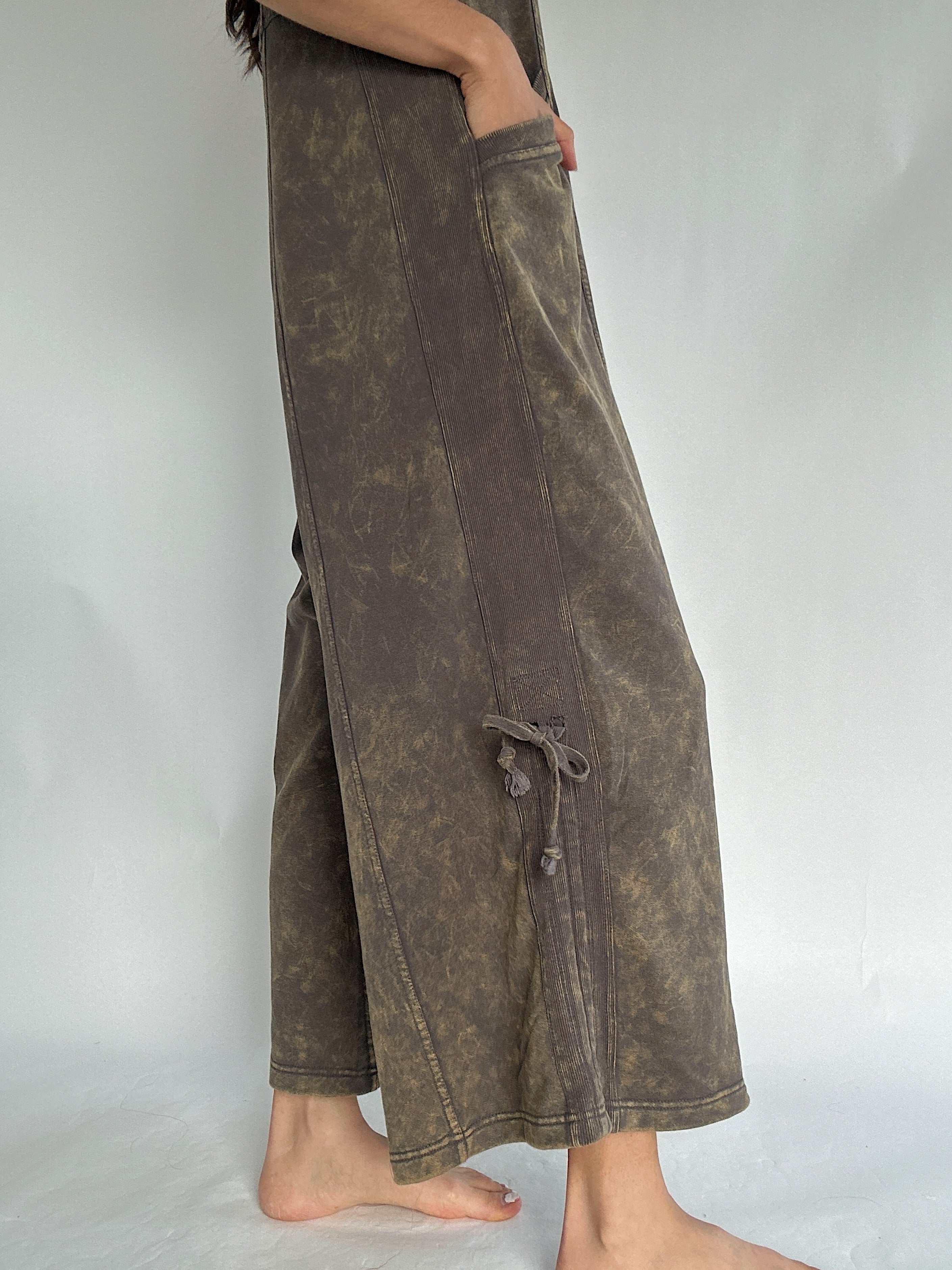 Brown wide-leg jumpsuit worn by a person on a plain background to show the cinchable tie accent