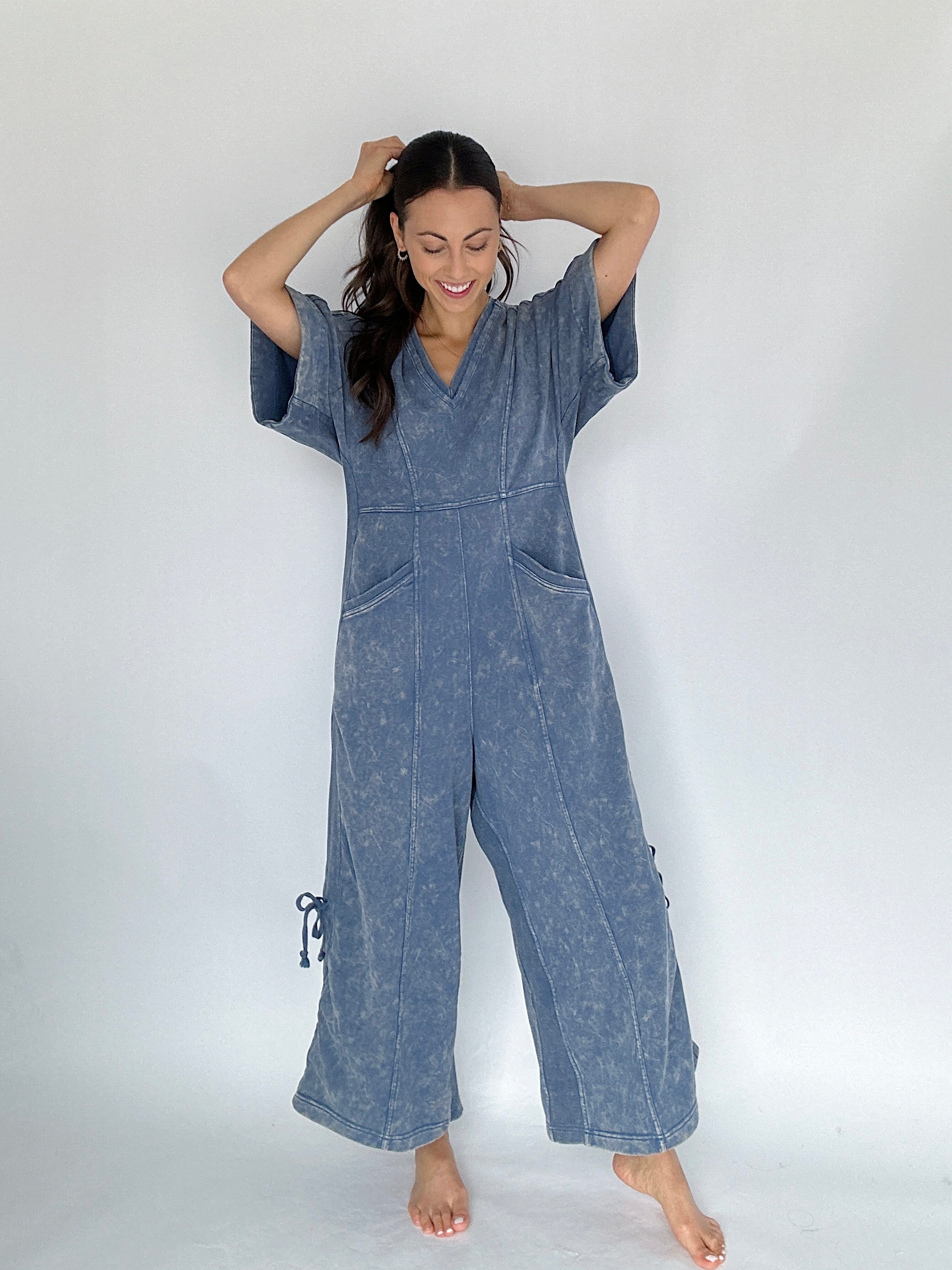 Woman wearing a blue jumpsuit against a white background from the front
