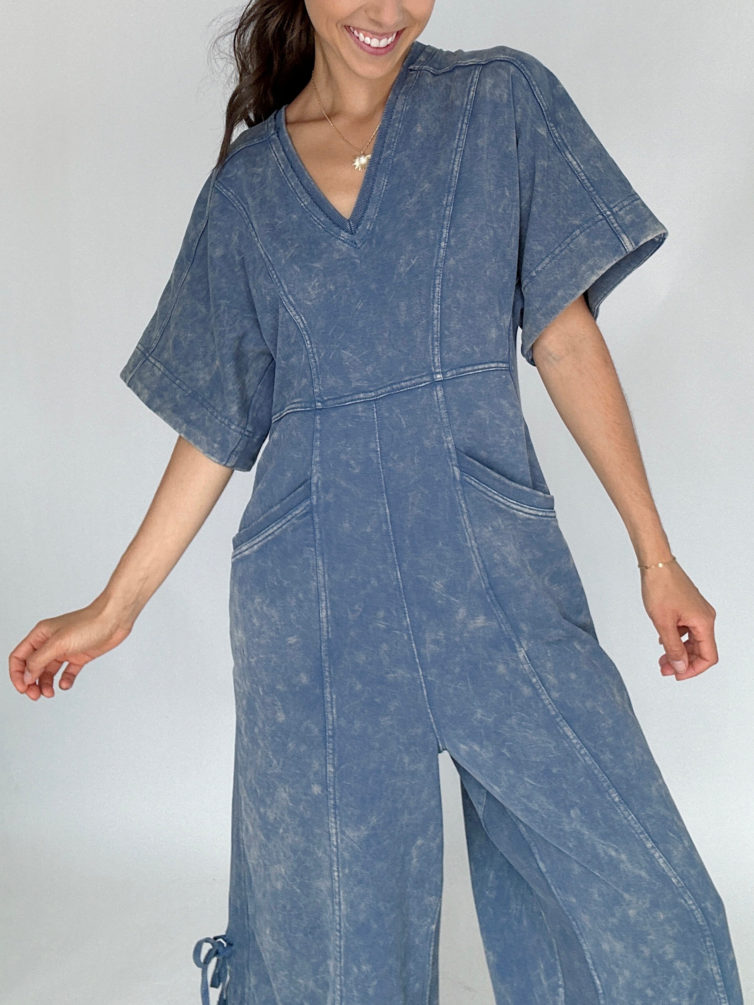 Woman wearing a blue denim jumpsuit against a plain background close up of top