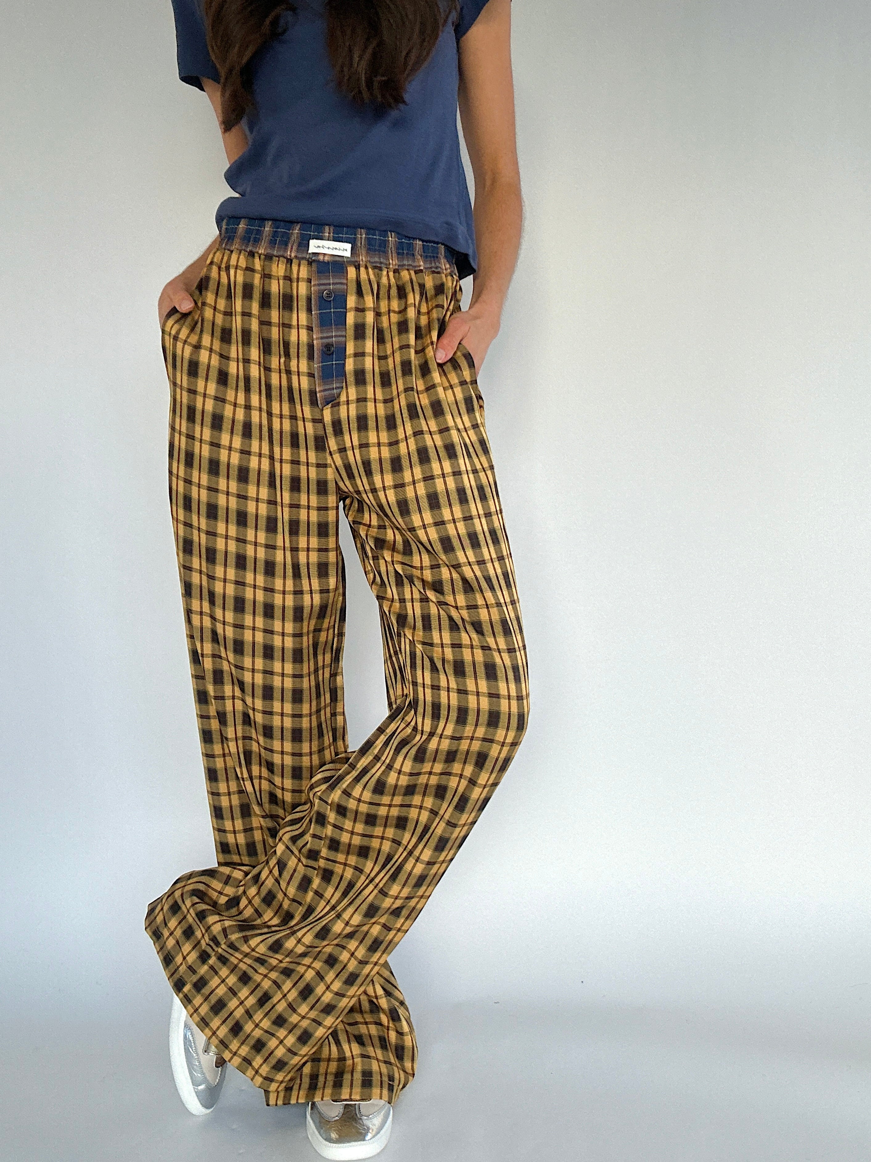 Person wearing mustard plaid pants and a blue shirt on a plain background