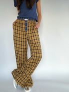Person wearing mustard plaid pants and a blue shirt on a plain background