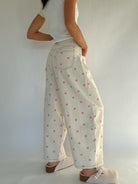 Person wearing a white top and polka dot pants against a plain background