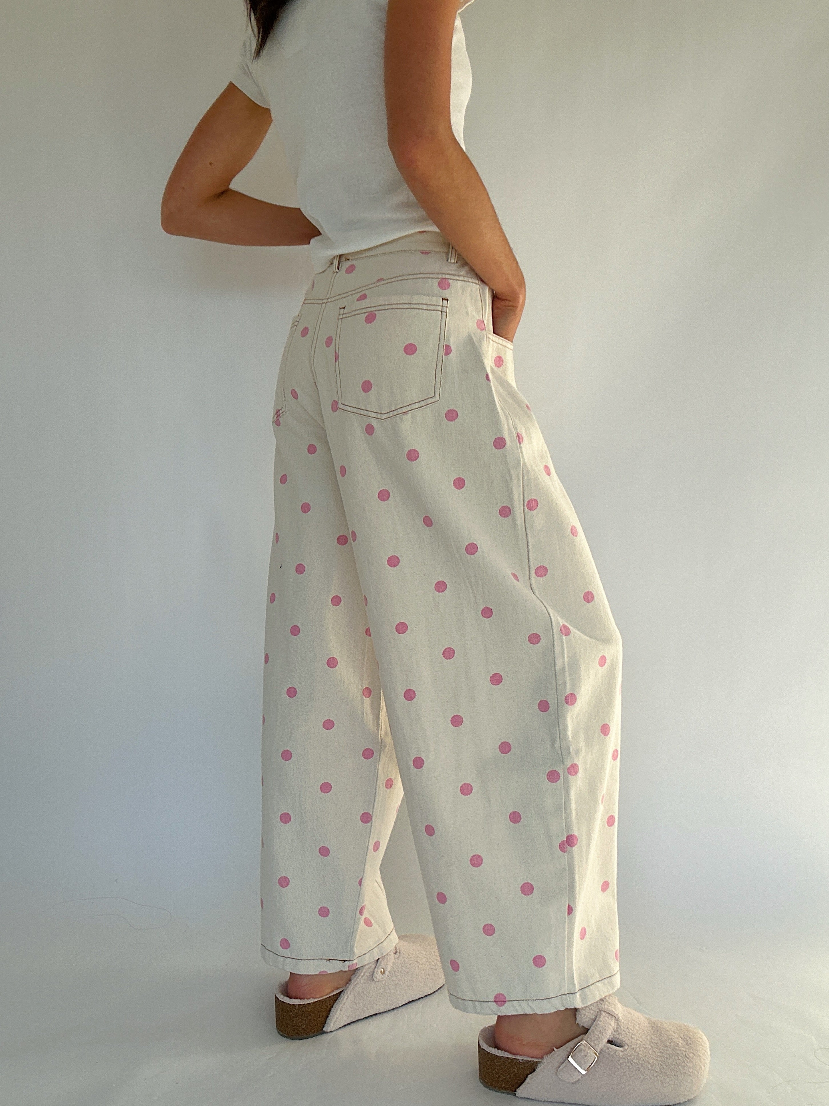 Person wearing a white top and polka dot pants against a plain background