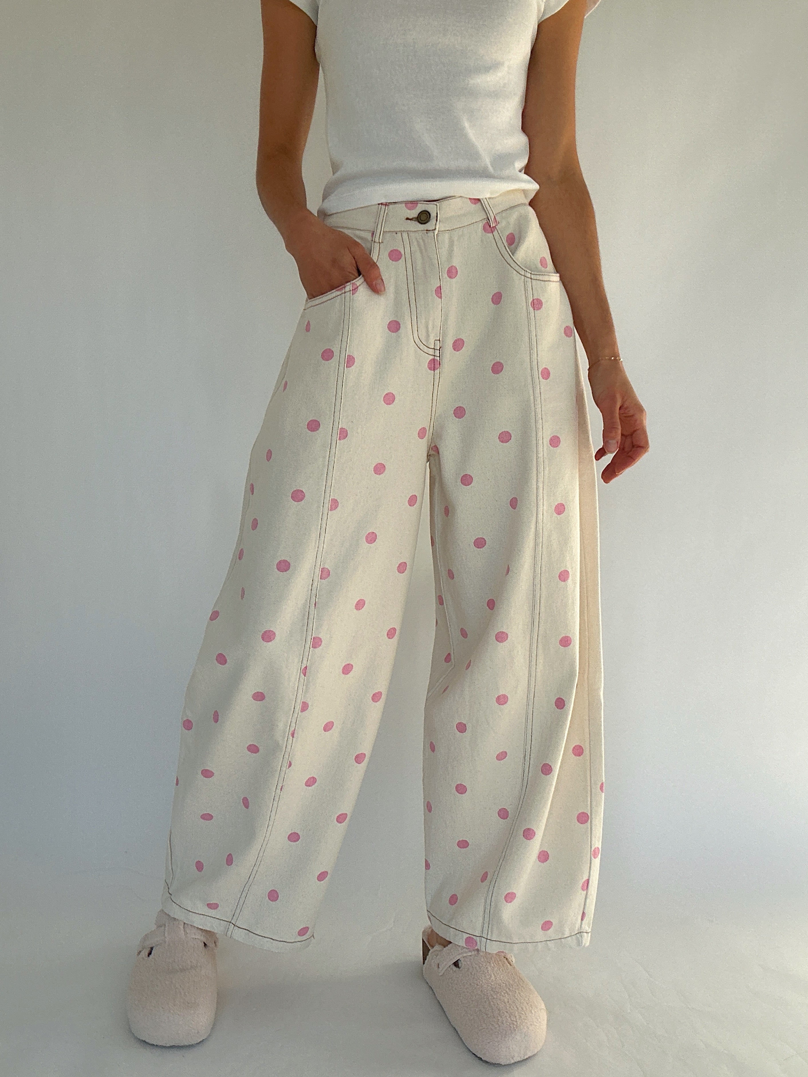 Person wearing white polka dot pants on a plain background