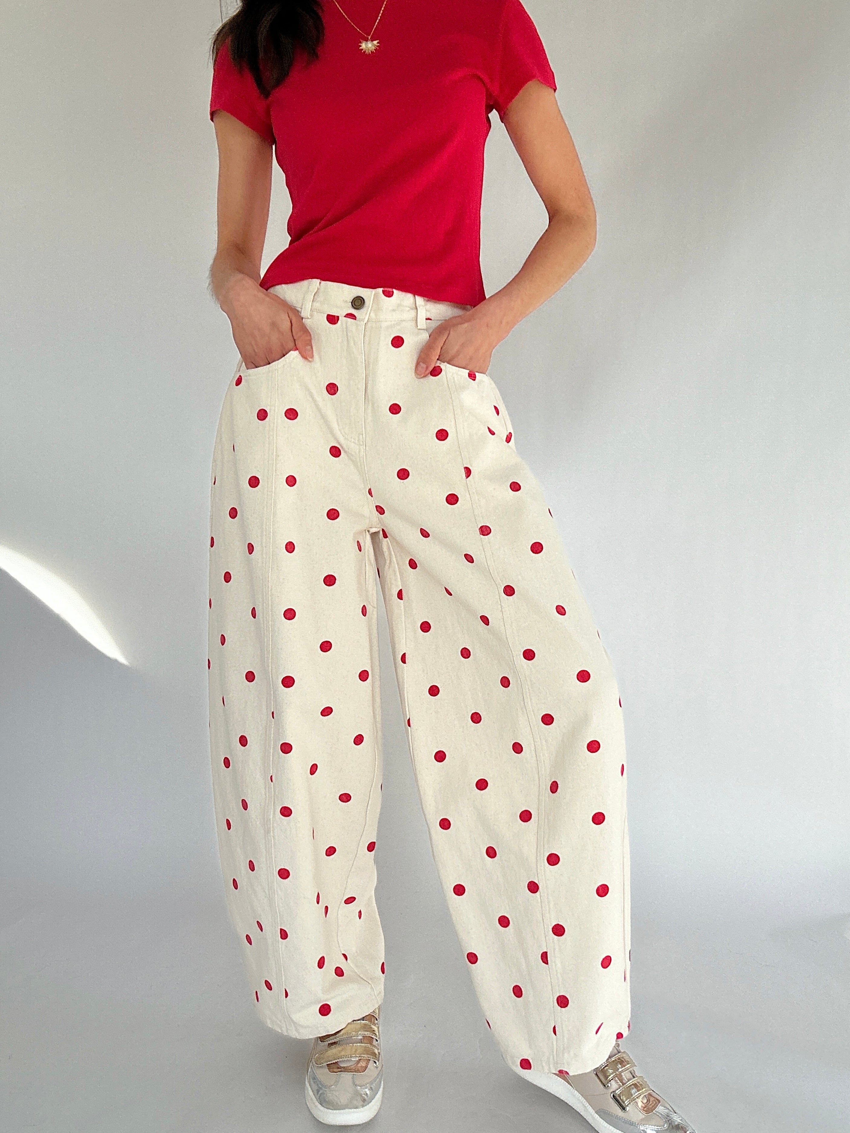 Person wearing a red shirt and white pants with red polka dots on a plain background