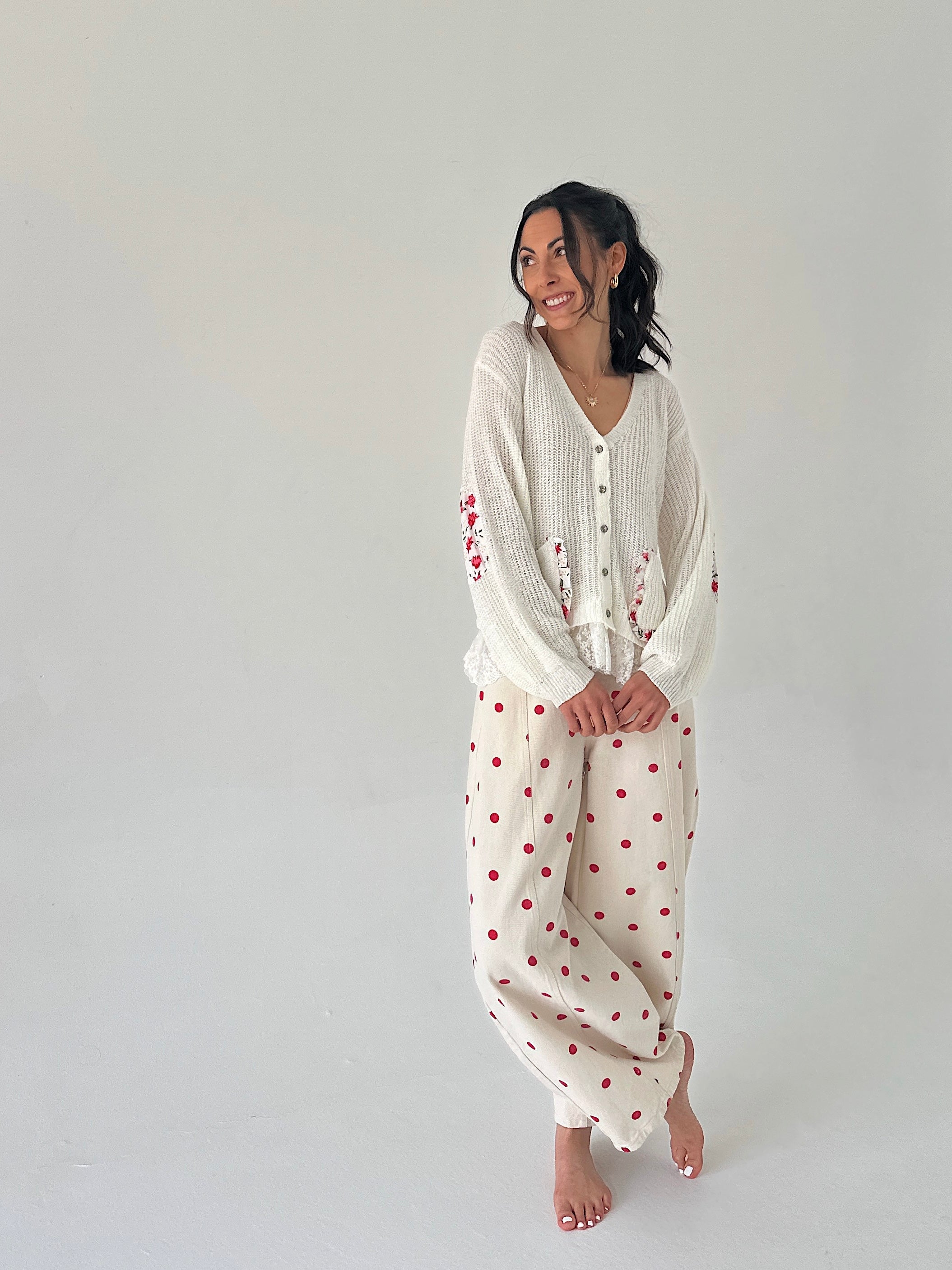 Woman wearing a white outfit with red patterns on a plain background