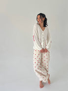 Woman wearing a white outfit with red patterns on a plain background