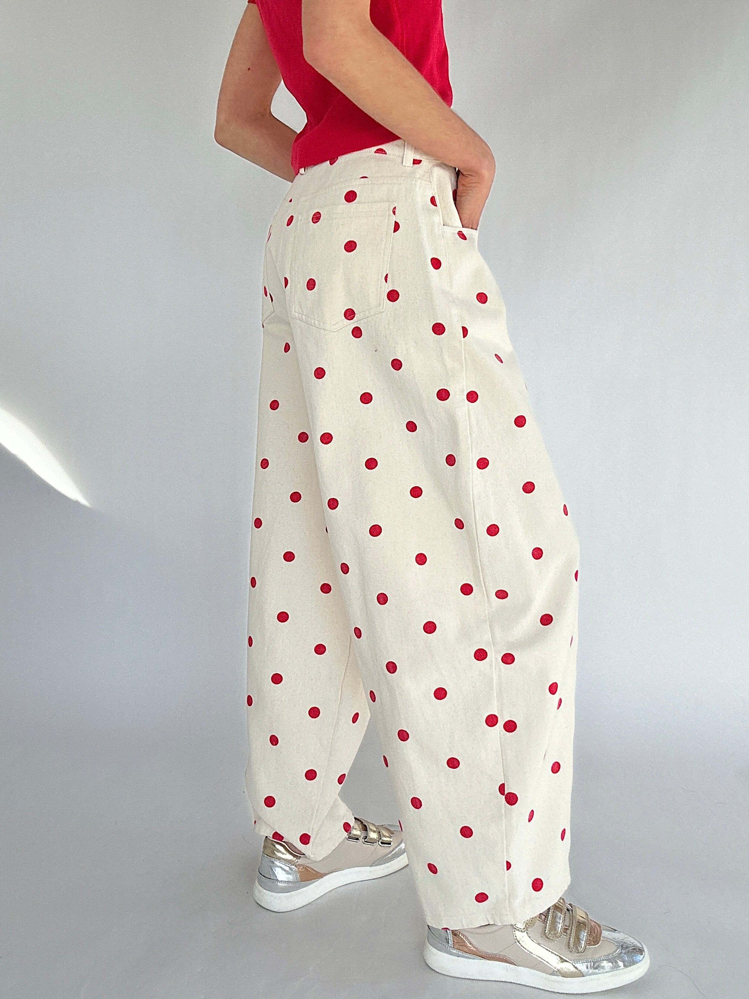 White pants with red polka dots worn by a person on a plain background